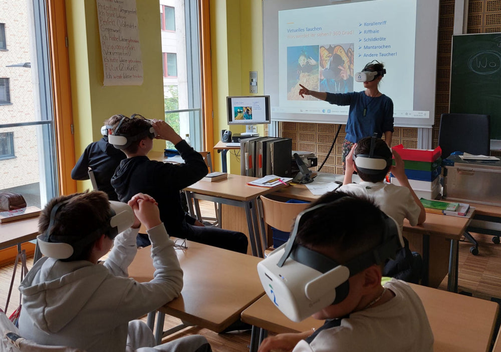 Un'insegnante e studenti indossano occhiali VR come accessori per immersioni virtuali in classe.