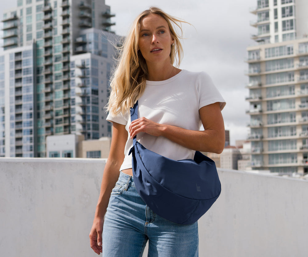 MOON BAG LARGE sac en deep ocean (bleu marine foncé) porté en bandoulière par une femme.