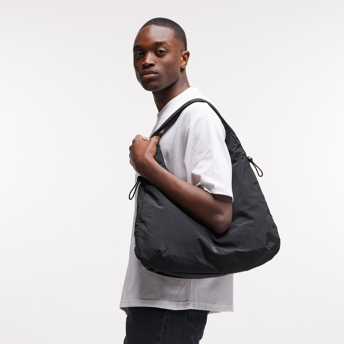 MELLOW BAG Tasche in black (Schwarz) von einem Mann über der Schulter getragen.