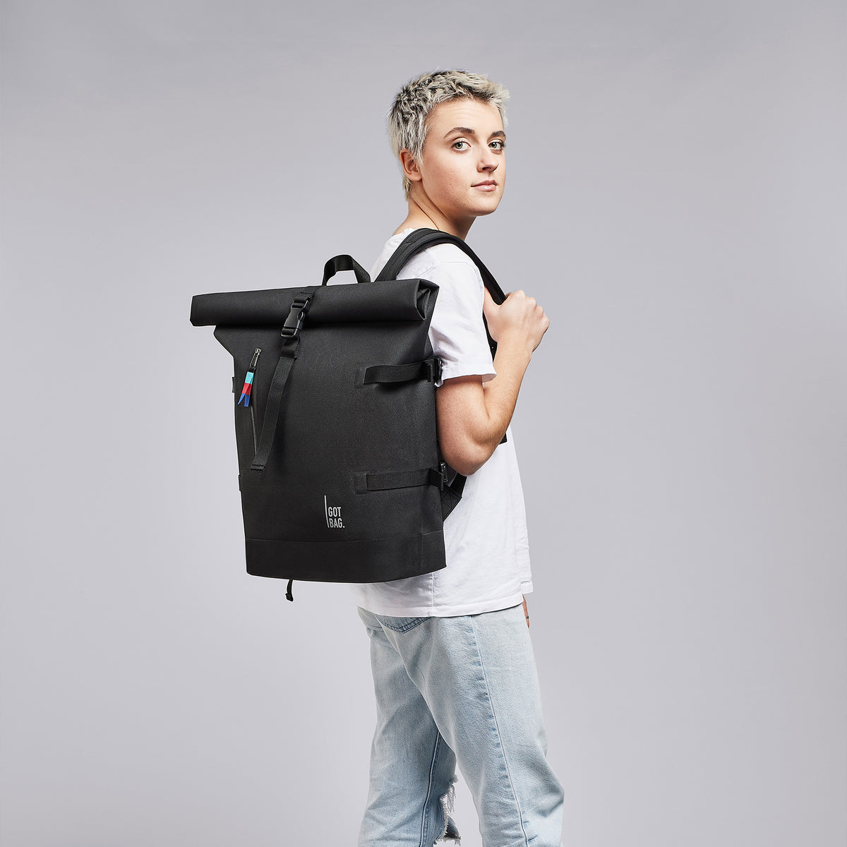 ROLLTOP Rucksack in black (Schwarz) von einer Frau als Rucksack auf dem Rücken getragen.