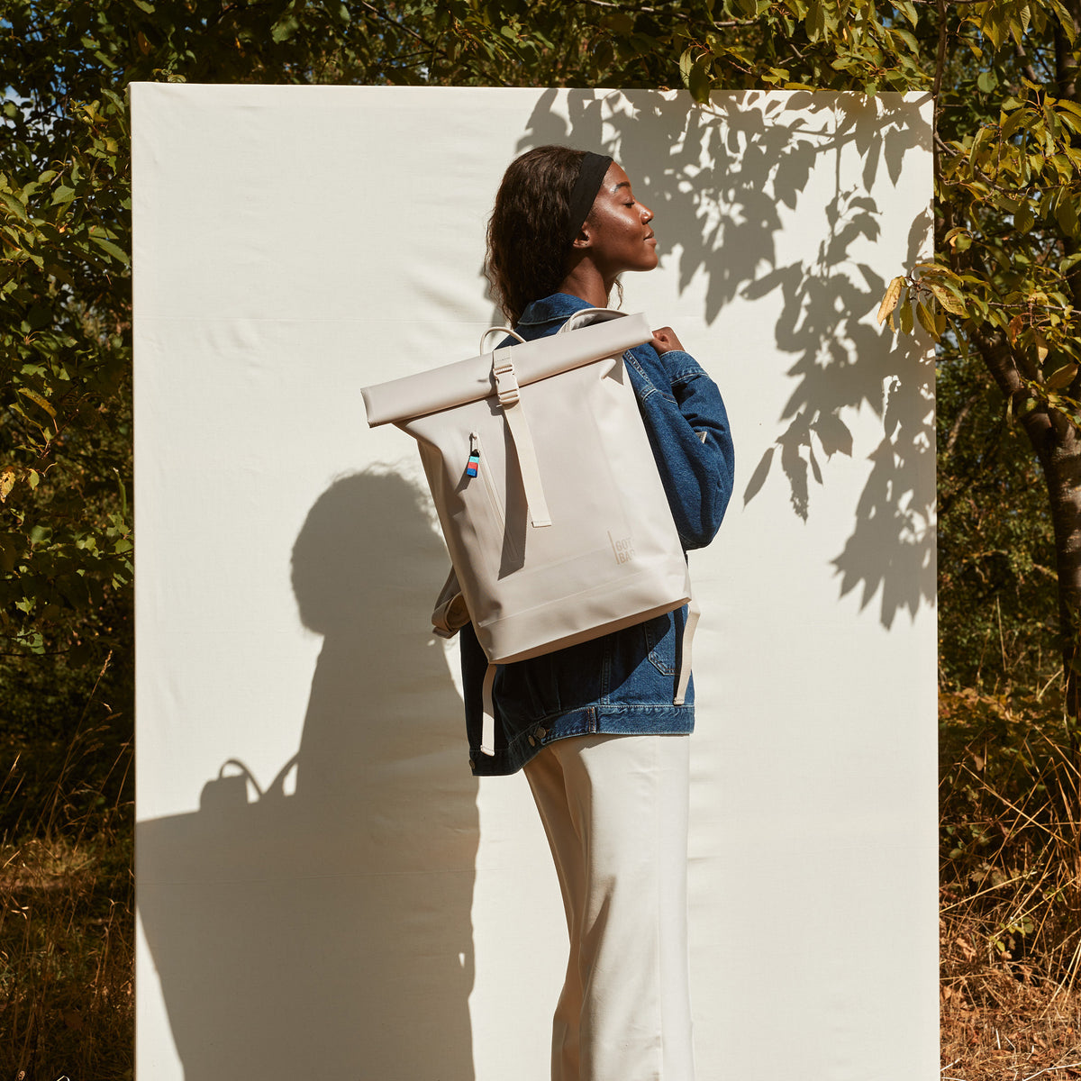 ROLLTOP LITE Rucksack in soft shell (warmes Cremeweiß) von einer Frau auf dem Rücken getragen.