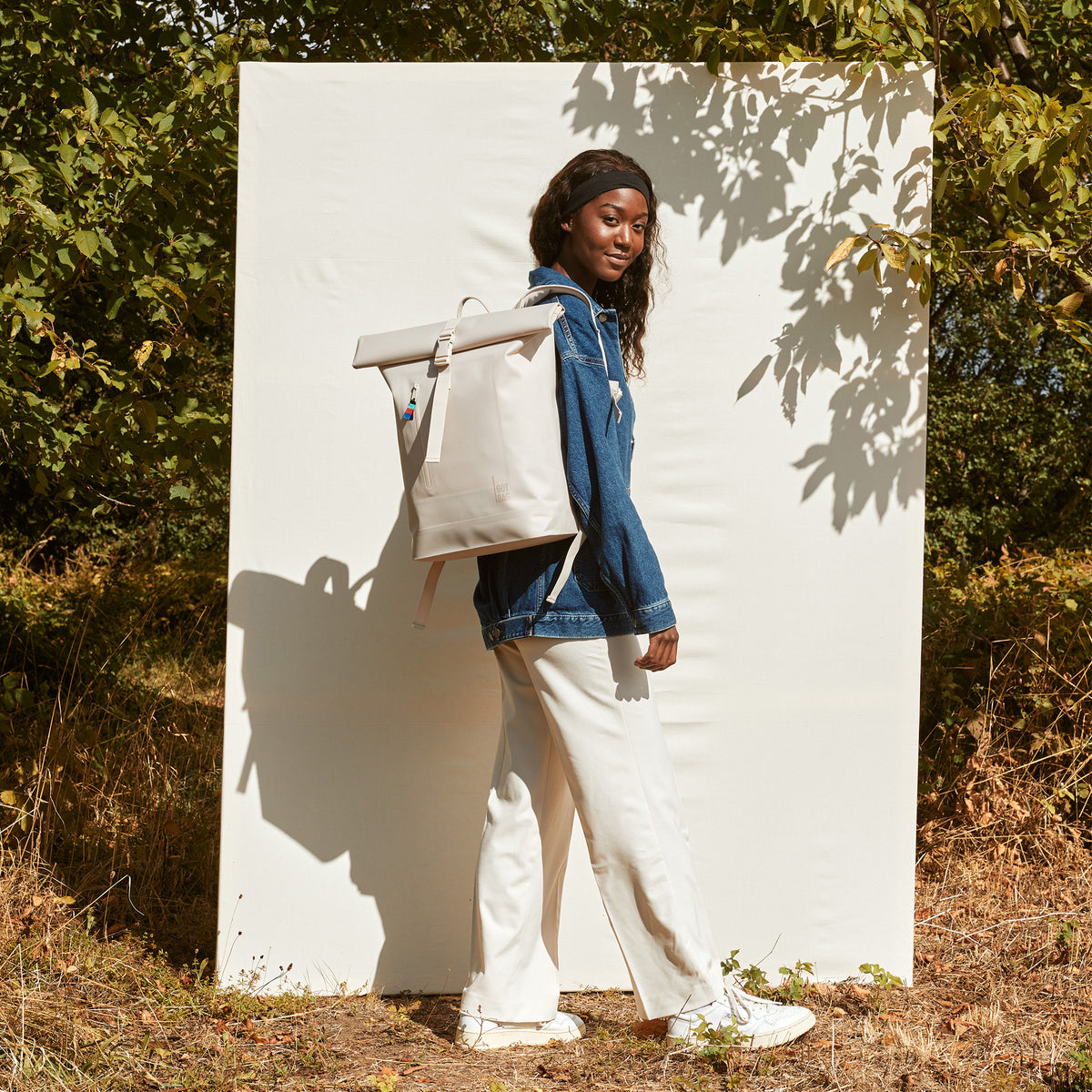 ROLLTOP LITE Rucksack in soft shell (warmes Cremeweiß) von einer Frau auf dem Rücken getragen.