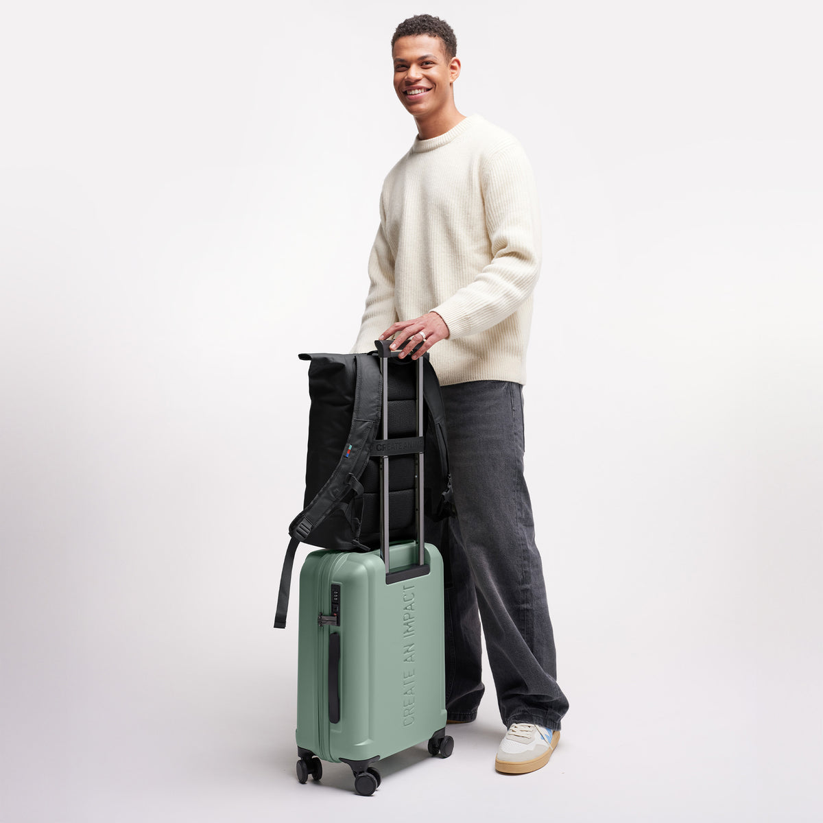RE SHELL CABIN 2.0 Koffer in reef (intensives Salbeigrün) von einem Mann mit Rucksack auf dem Koffer.