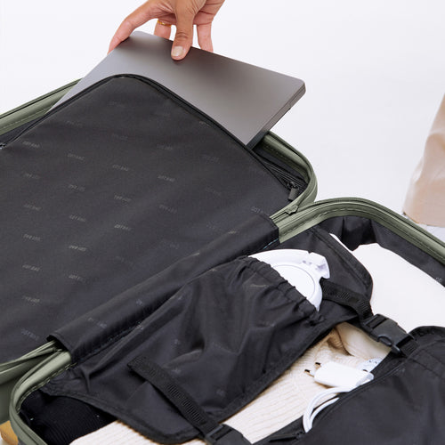 RE SHELL Cabin Koffer in bass (Salbeigrün), ein Laptop wird in ein Fach gelegt.