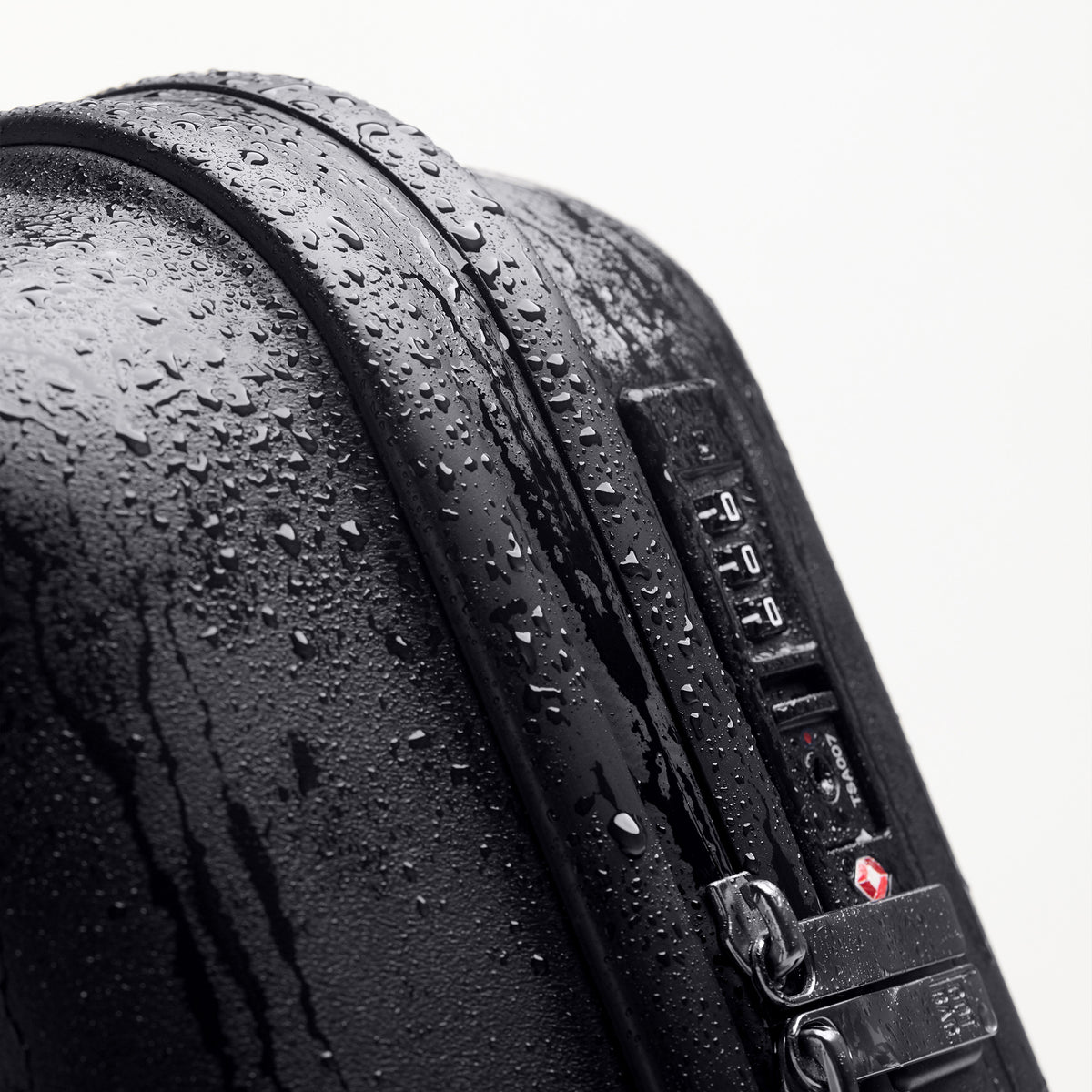 RE SHELL Koffer in black (Schwarz) als Detailaufnahme mit Wassertropfen und Zahlenschloss.