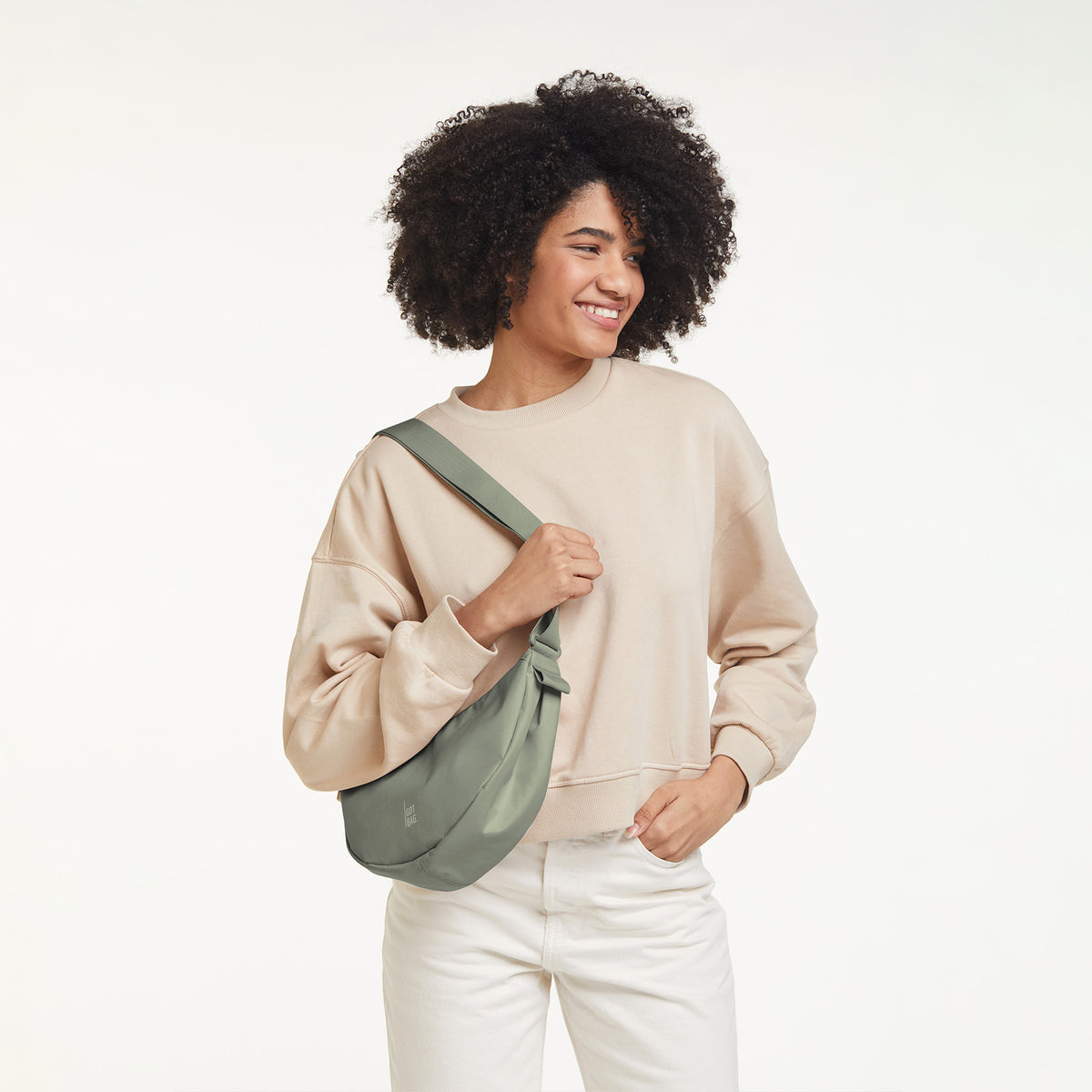 MOON BAG SMALL Tasche in bass (Salbeigrün) von einer Frau crossbody getragen.