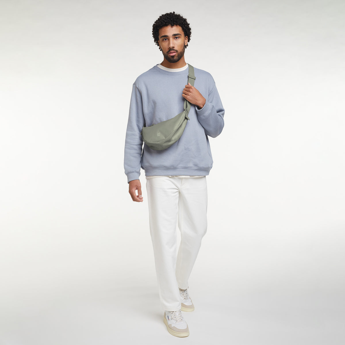 MOON BAG SMALL Tasche in bass (Salbeigrün) von einem Mann crossbody getragen.