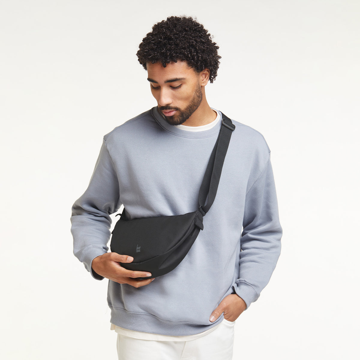 MOON BAG SMALL Tasche in black (Schwarz) von einem Mann crossbody getragen.