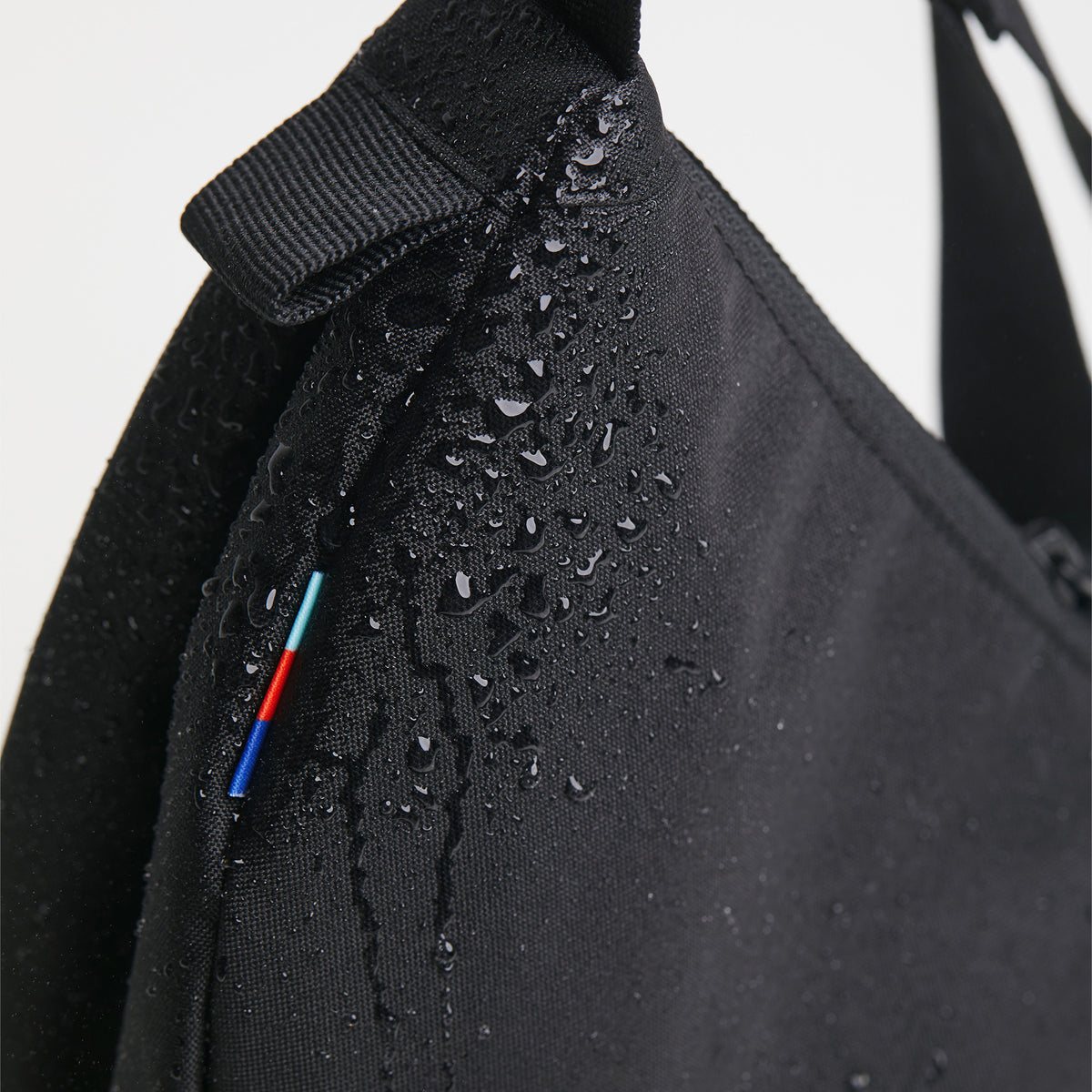 MOON BAG SMALL Tasche in black (Schwarz) mit Wassertropfen auf der Oberfläche und bunten Streifen.