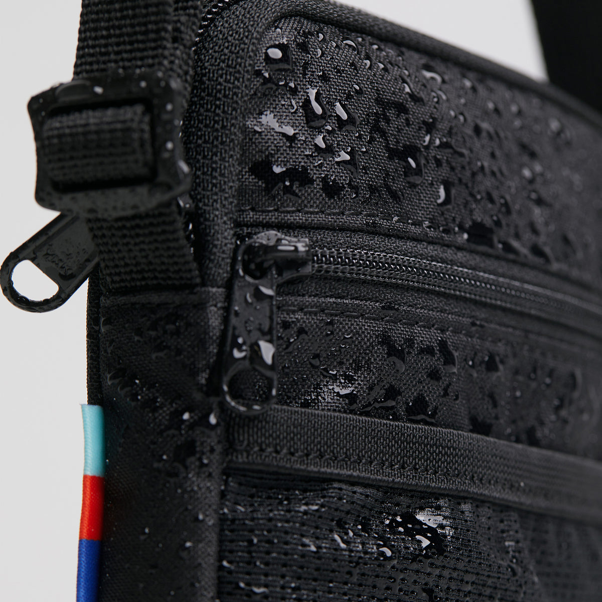 NANO BAG Tasche in black (Schwarz) als Detailaufnahme mit Wassertropfen auf der Oberfläche.
