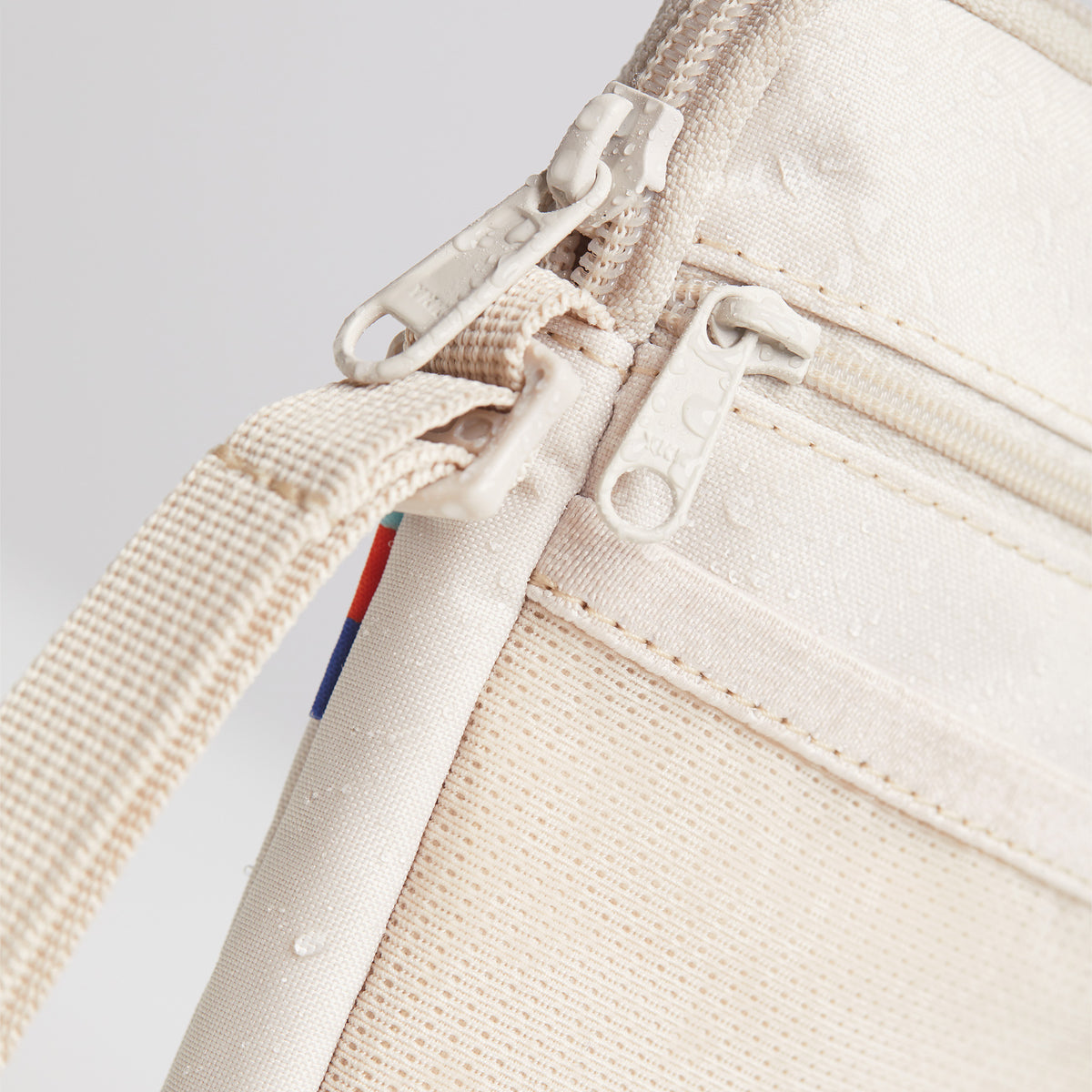 NANO BAG Tasche in soft shell (warmes Cremeweiß) mit Wassertropfen als Detailaufnahme.