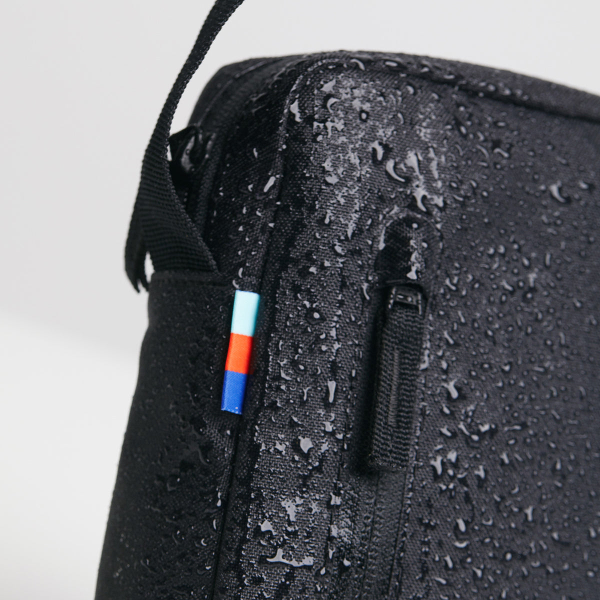 PUSHER BAG Tasche in black (Schwarz) als Detailaufnahme mit Wassertropfen auf der Oberfläche.