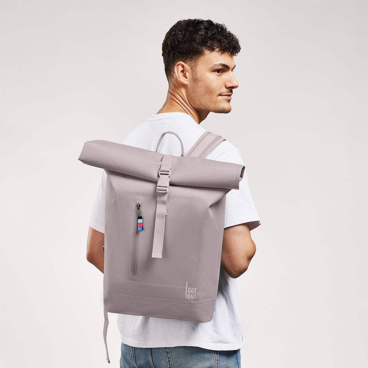 ROLLTOP LITE Rucksack in seahorse (graues Pastellrosa) von einem Mann auf dem Rücken getragen.