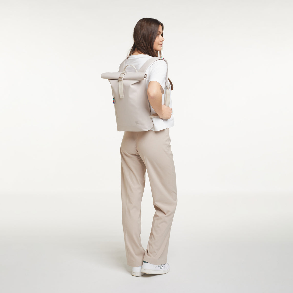 ROLLTOP SMALL Rucksack in soft shell (warmes Cremeweiß) von einer Frau als Rucksack auf dem Rücken getragen.