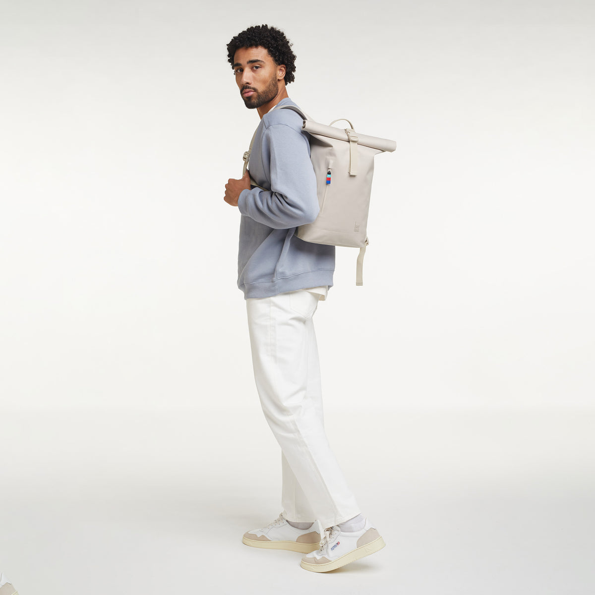 ROLLTOP SMALL Rucksack in soft shell (warmes Cremeweiß) von einem Mann als Rucksack auf dem Rücken getragen.