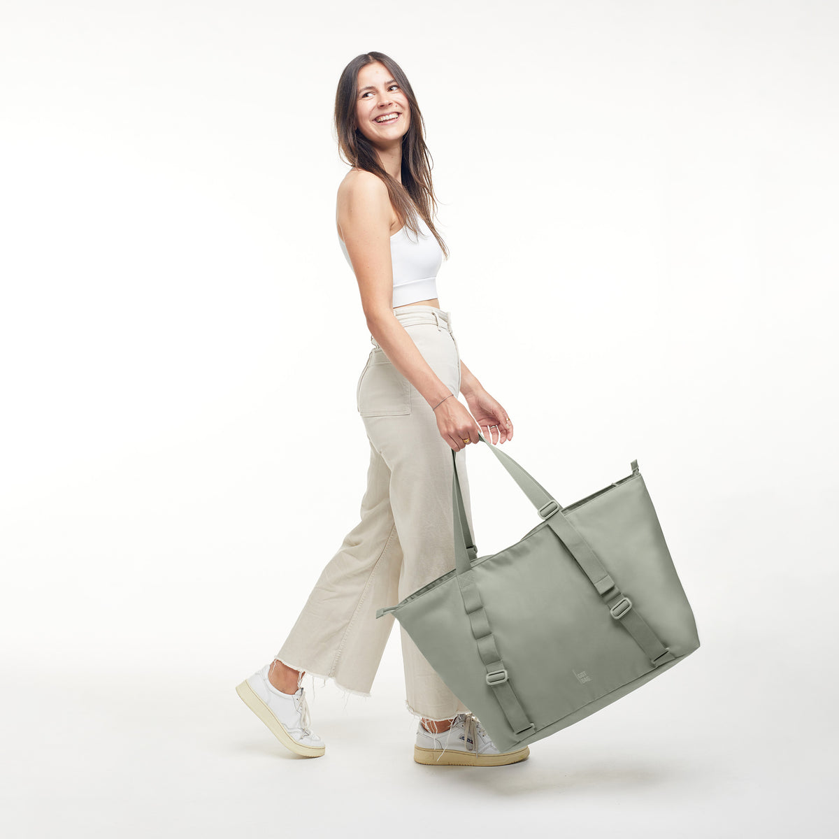 TOTE BAG Tasche in bass (Salbeigrün) von einer Frau in der Hand gehalten.