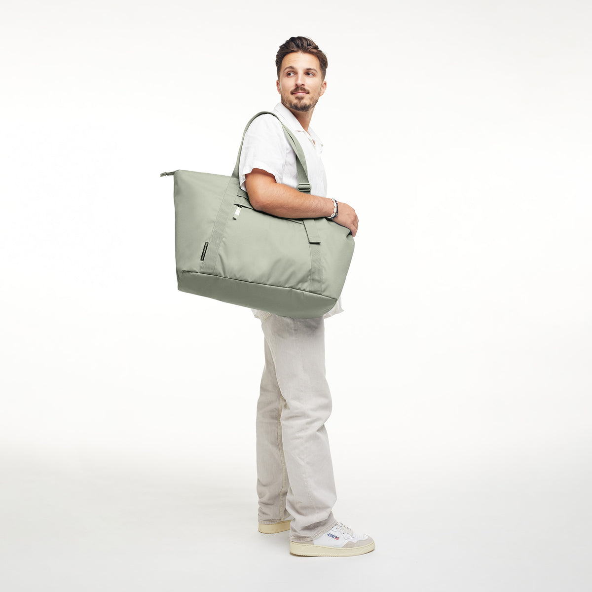 TOTE BAG Tasche in bass (Salbeigrün) von einem Mann über der Schulter getragen.