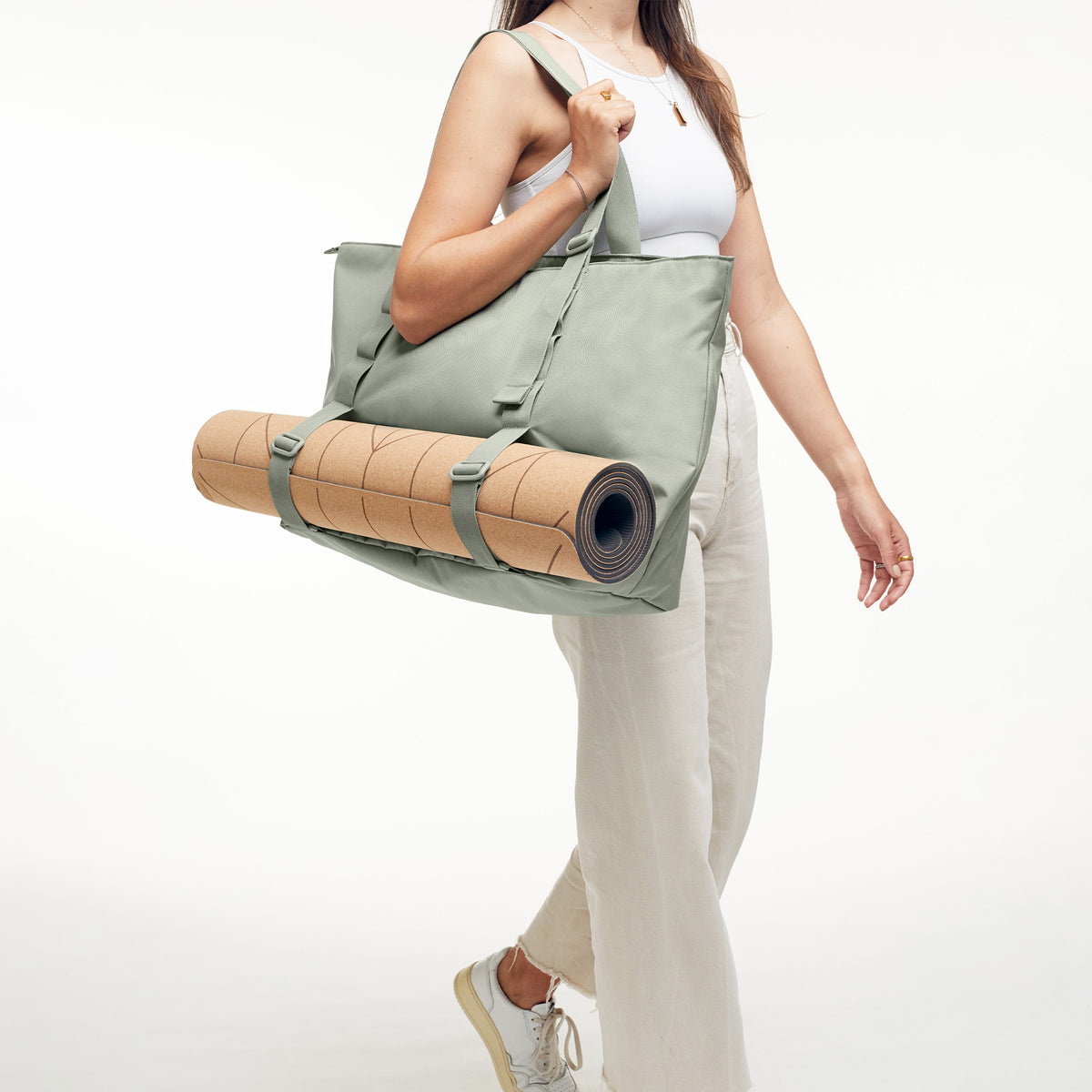 TOTE BAG Tasche in bass (Salbeigrün) von einer Frau mit befestigter Yogamatte über der Schulter getragen.