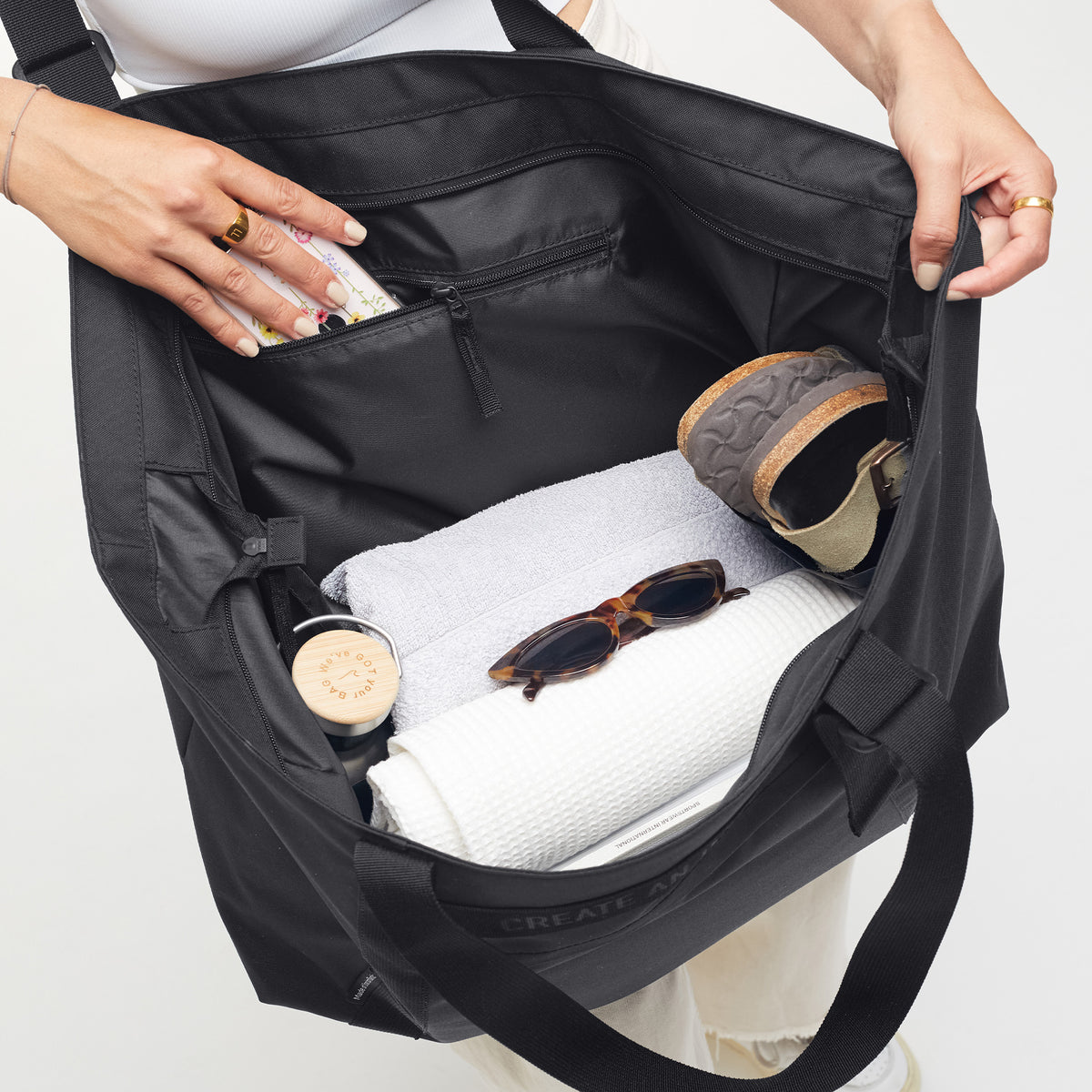 TOTE BAG Monochrome Edition Tasche in black (Schwarz), von einer Frau geöffnet und in den Innenraum blickend.