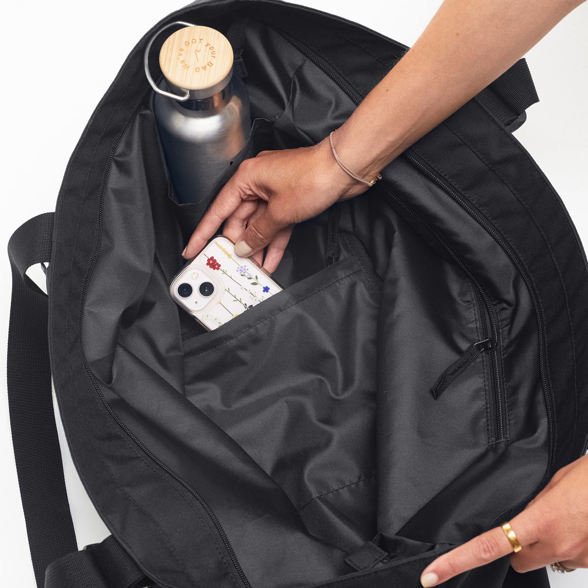 TOTE BAG Tasche in black (Schwarz) mit einer Frau, die in die Innentasche greift.