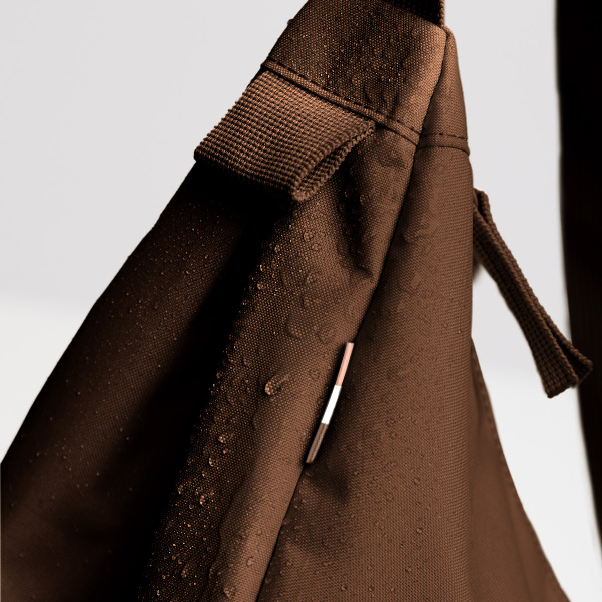 MOON BAG LARGE Tasche in trench (warmes Goldbraun) als Detailaufnahme mit Wassertropfen.