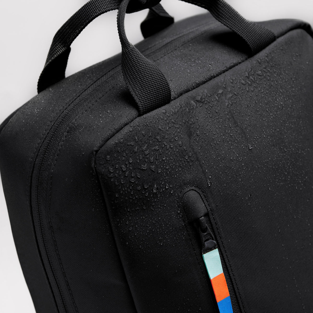DAYPACK 2.0 Rucksack in black (Schwarz), Detailaufnahme mit Wassertropfen & farbigem Zipper.