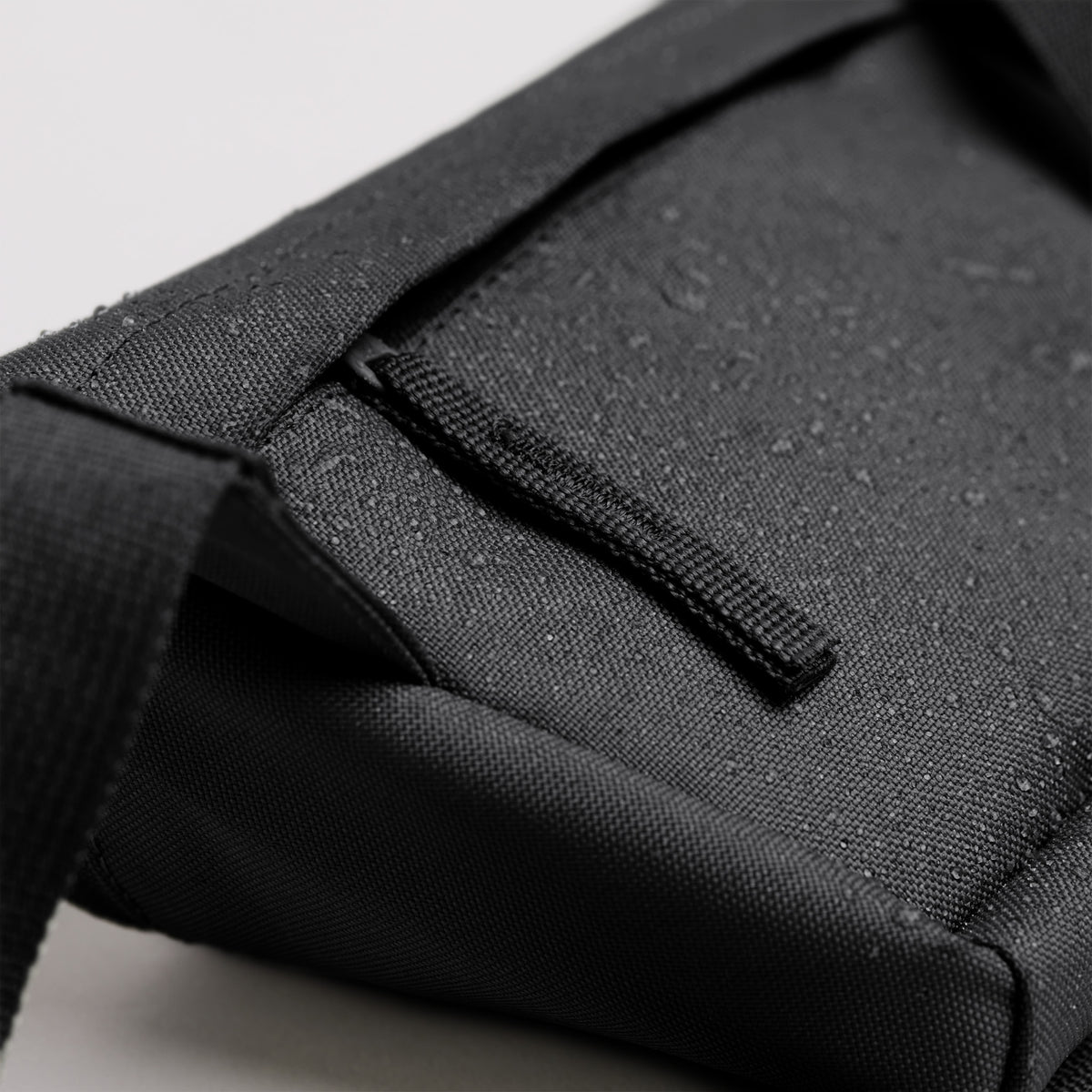 Detailaufnahme einer HIP BAG 2.0 Tasche in black (Schwarz) mit Wassertropfen auf dem Stoff.