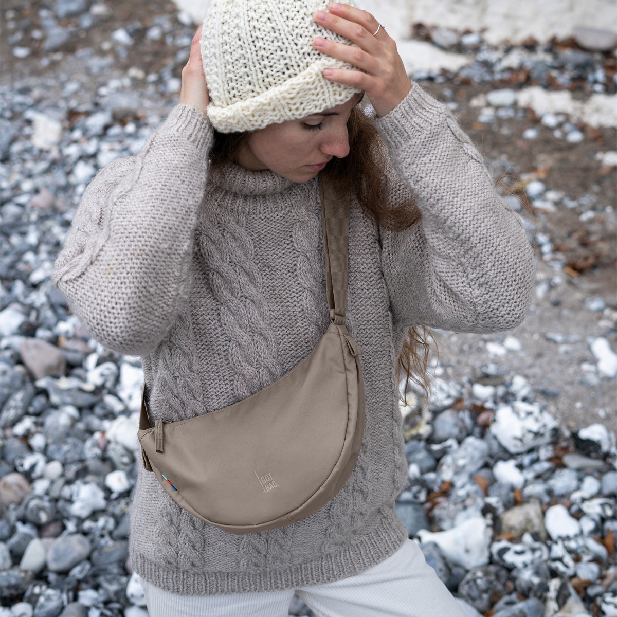 MOONBAG SMALL Tasche in seal (dunkler Beigeton) von einer Frau crossbody getragen.