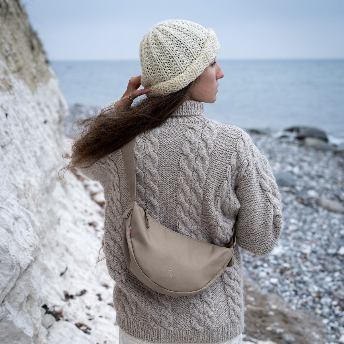 MOONBAG SMALL Tasche in seal (dunkler Beigeton) von einer Frau crossbody getragen.