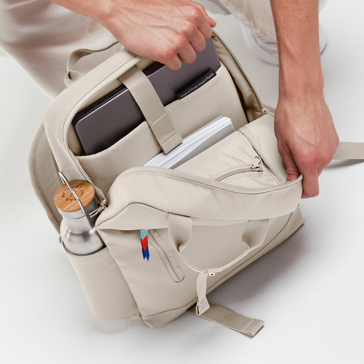 DAYPACK Rucksack in soft shell (warmes Cremeweiß), ein Mann packt den geöffneten Rucksack.