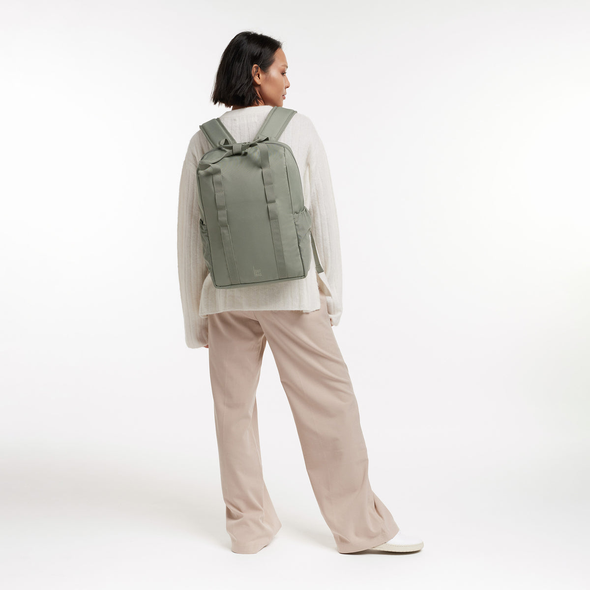 DAYPACK LOOP Rucksack in bass (Salbeigrün) von einer Frau auf dem Rücken getragen.