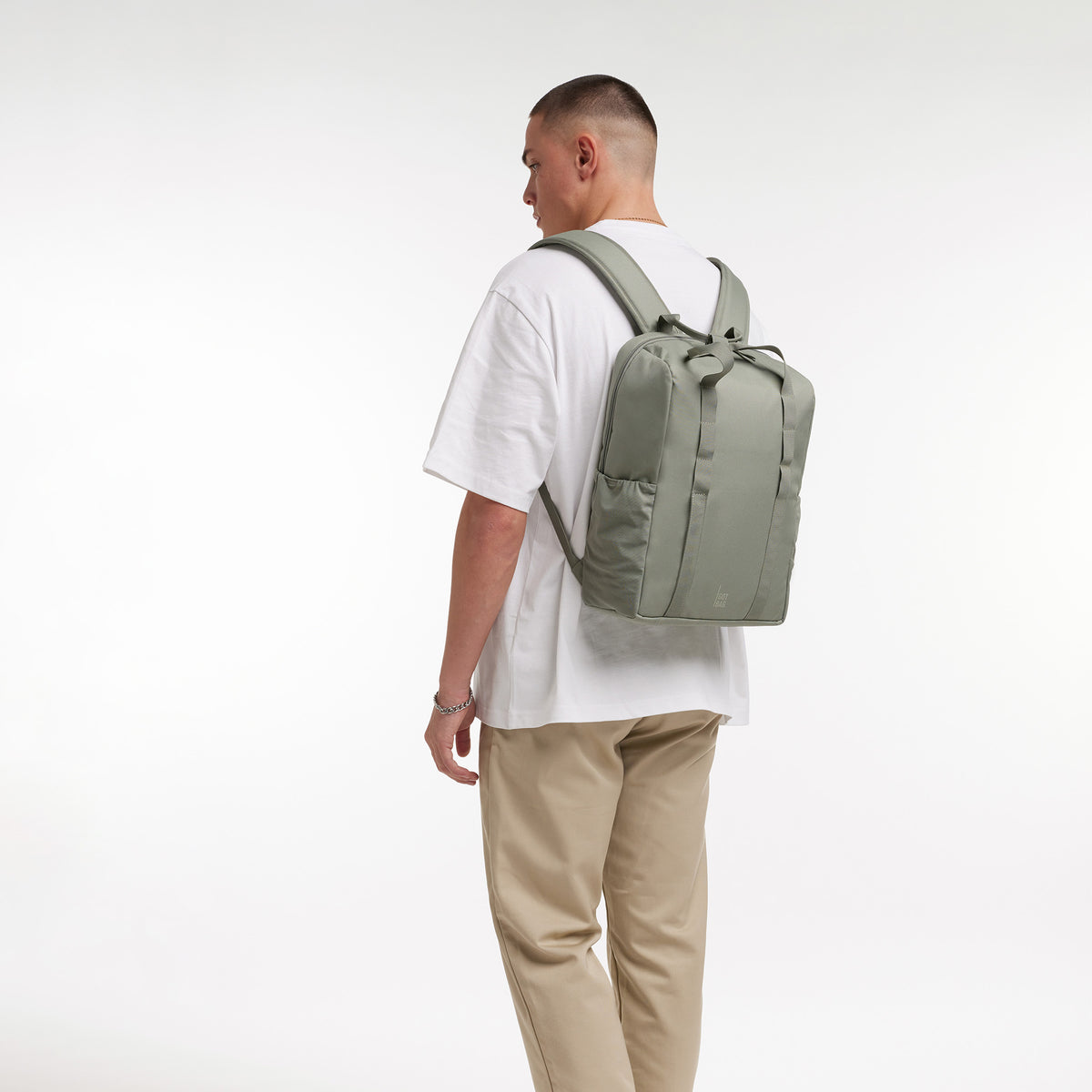 DAYPACK LOOP Rucksack in bass (Salbeigrün) von einem Mann als Rucksack auf dem Rücken getragen.