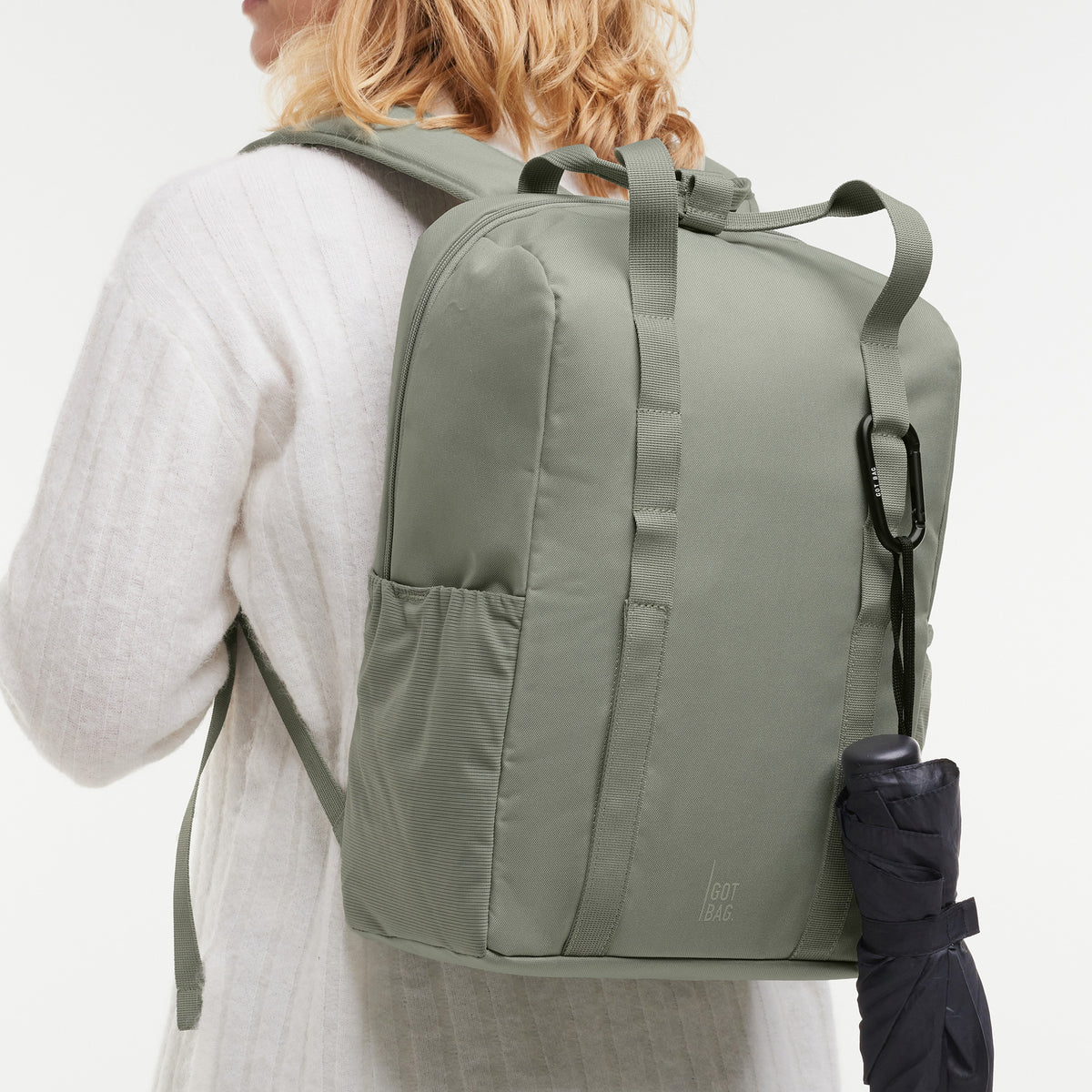 DAYPACK LOOP Rucksack in bass (Salbeigrün) von einer Frau auf dem Rücken getragen.