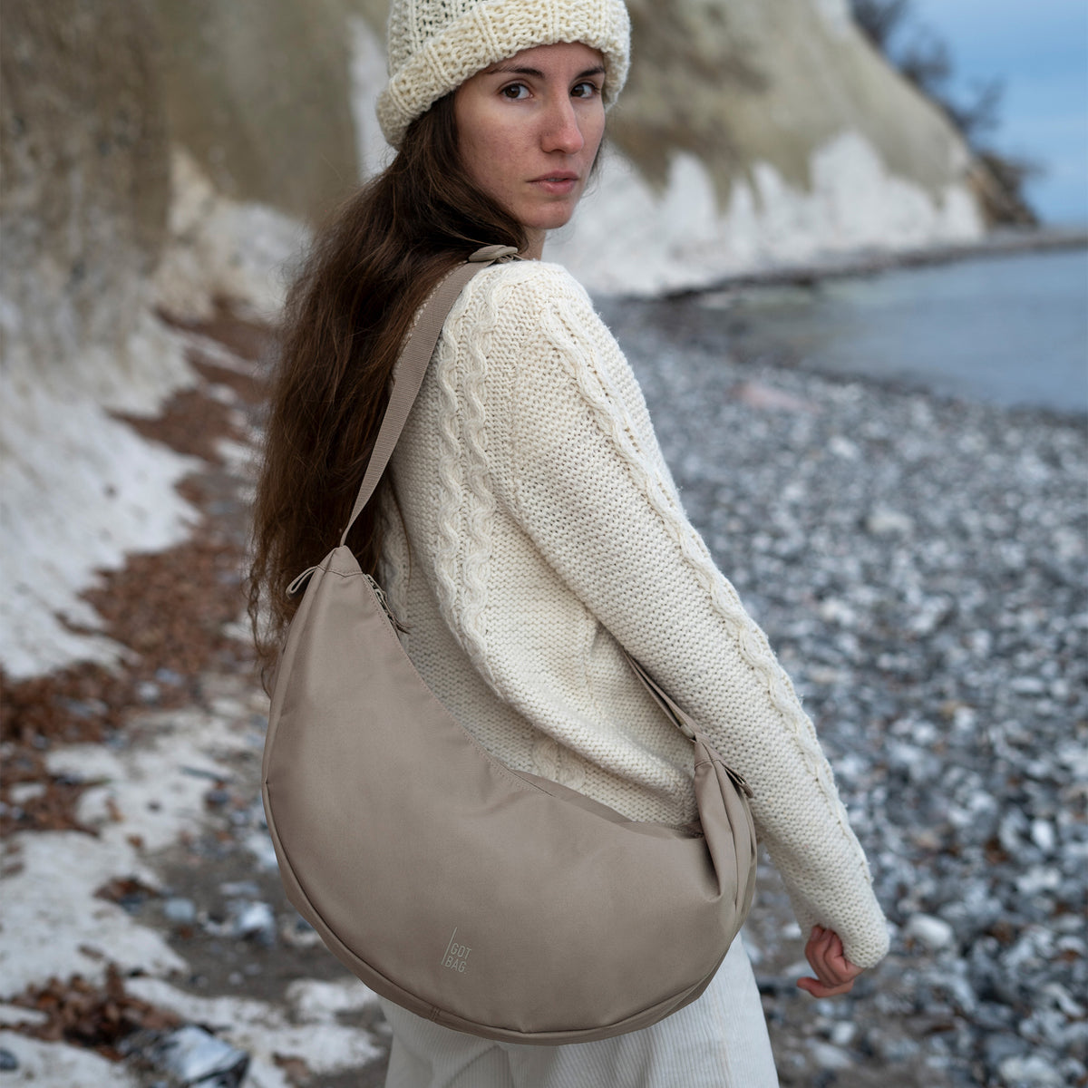 MOON BAG LARGE Tasche in seal (dunkler Beigeton) von einer Frau crossbody getragen.