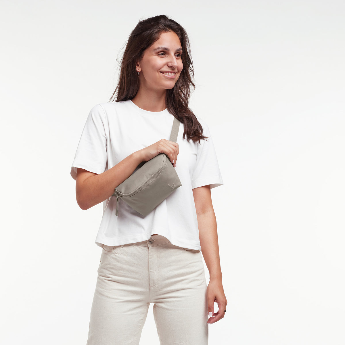HIP BAG 2.0 Tasche in scallop (helles Beige) von einer Frau crossbody getragen.