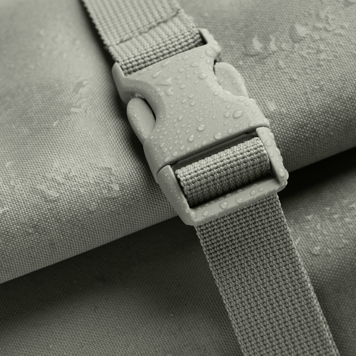 ROLLTOP Rucksack in bass (Salbeigrün) als Detailaufnahme der Schnalle mit Wassertropfen auf dem Stoff.
