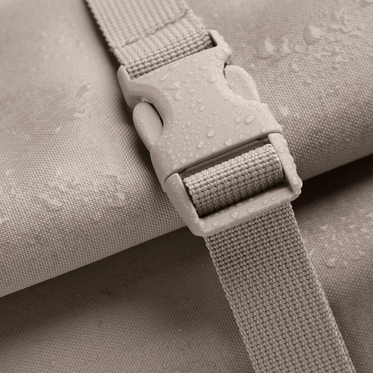 ROLLTOP 2.0 Rucksack in scallop (helles Beige) als Detailaufnahme mit Schnalle und Wassertropfen.