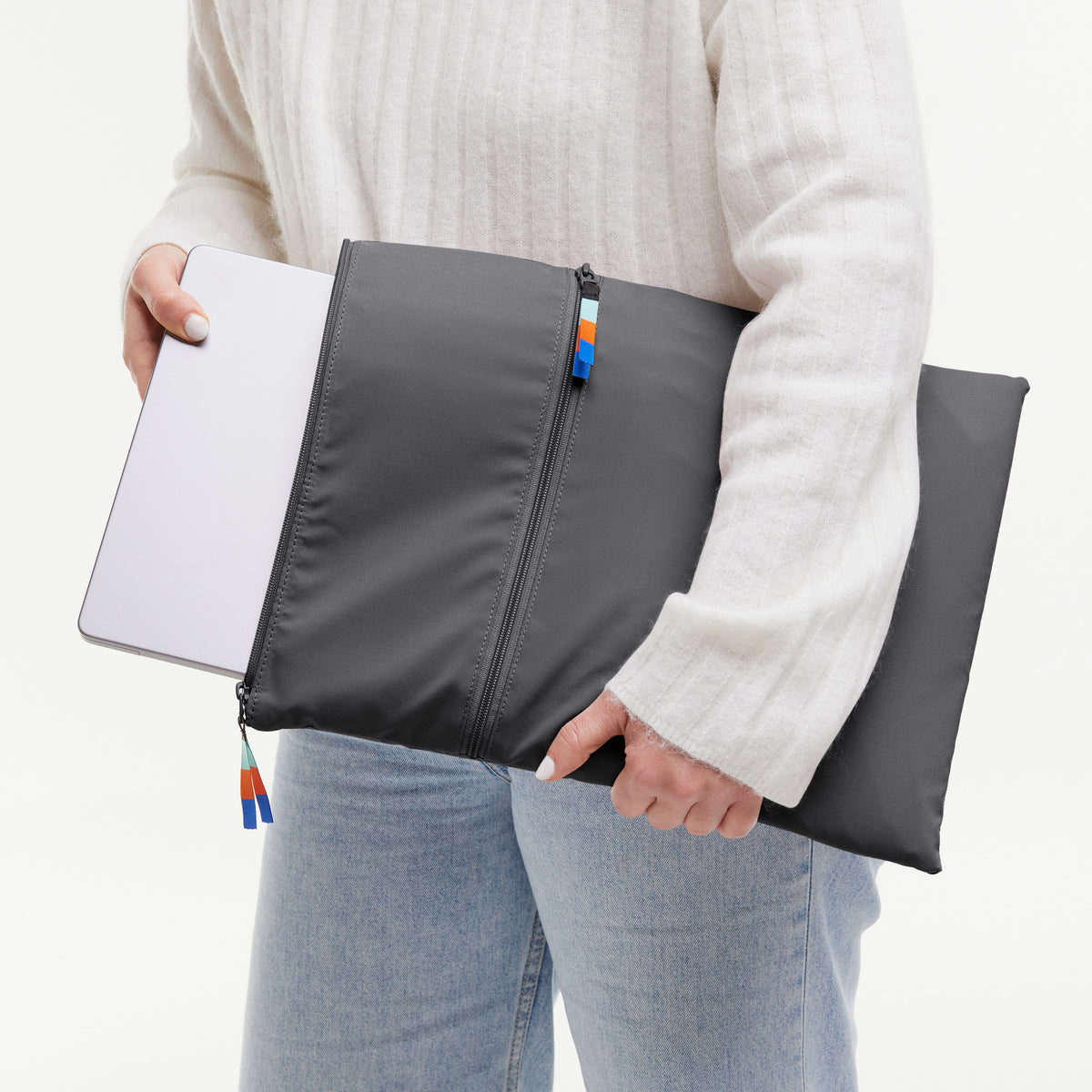 ROLLTOP Tasche in shark (Dunkelgrau), von einer Frau in der Hand gehalten, die einen Laptop hineinsteckt.