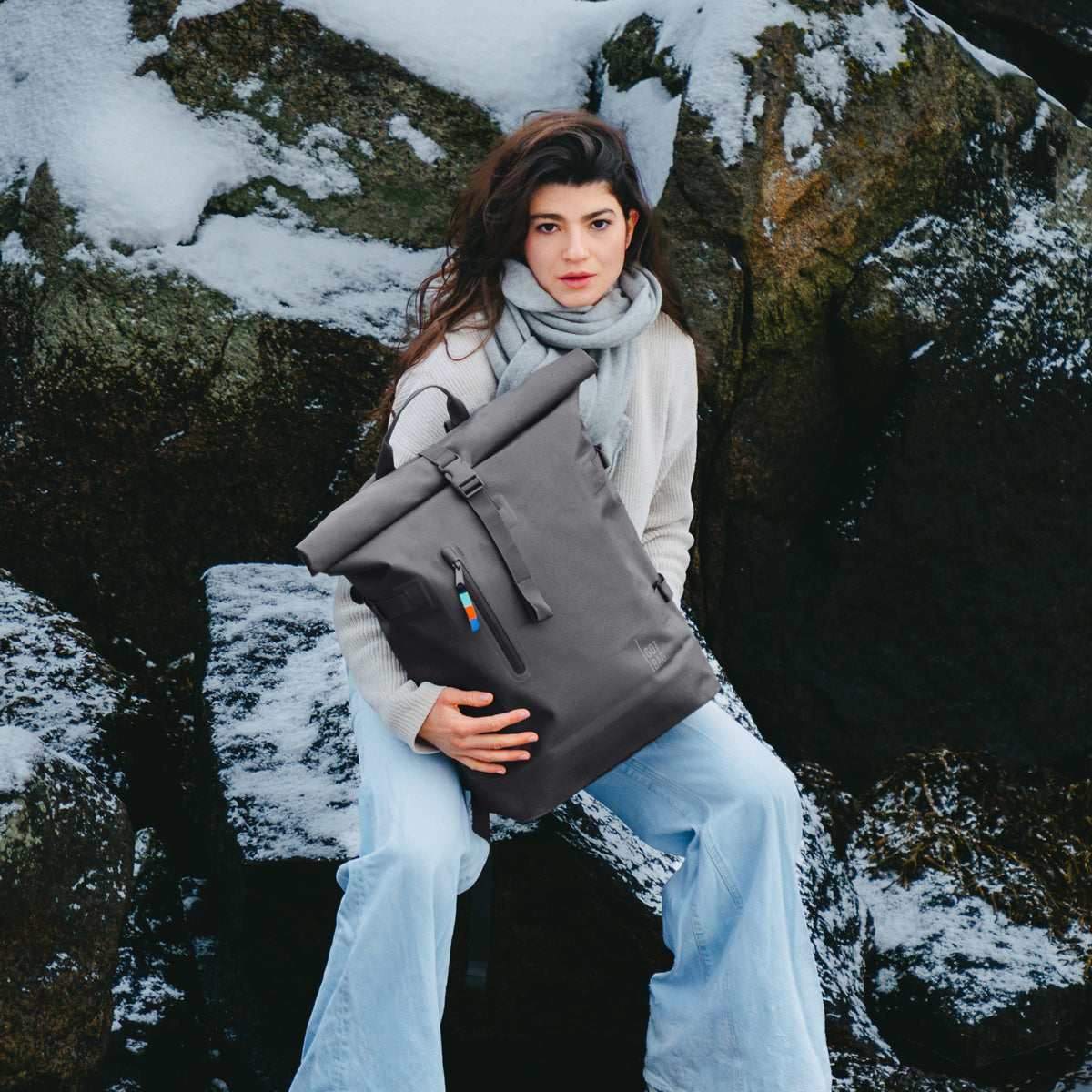 ROLLTOP Rucksack in shark (Dunkelgrau) von einer Frau im Schnee gehalten.