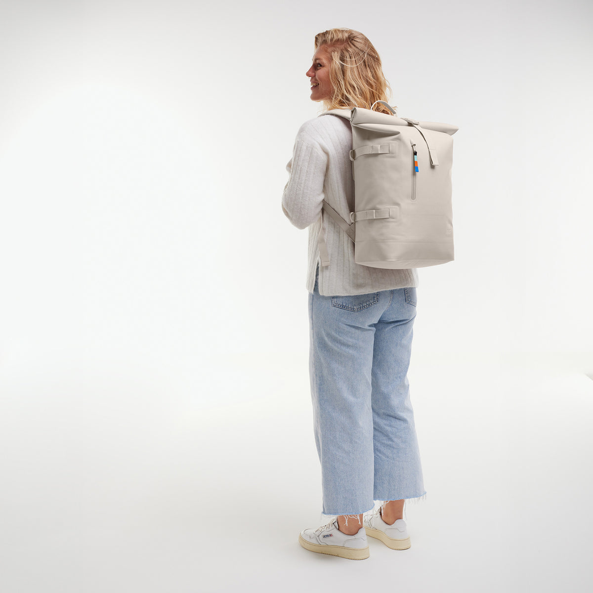 ROLLTOP 2.0 Rucksack in soft shell (warmes Cremeweiß) von einer Frau auf dem Rücken getragen.