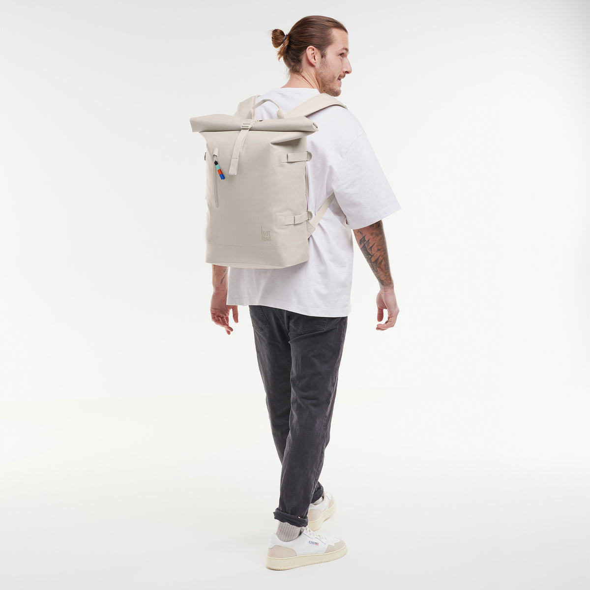 ROLLTOP Rucksack in soft shell (warmes Cremeweiß) von einem Mann als Rucksack auf dem Rücken getragen.