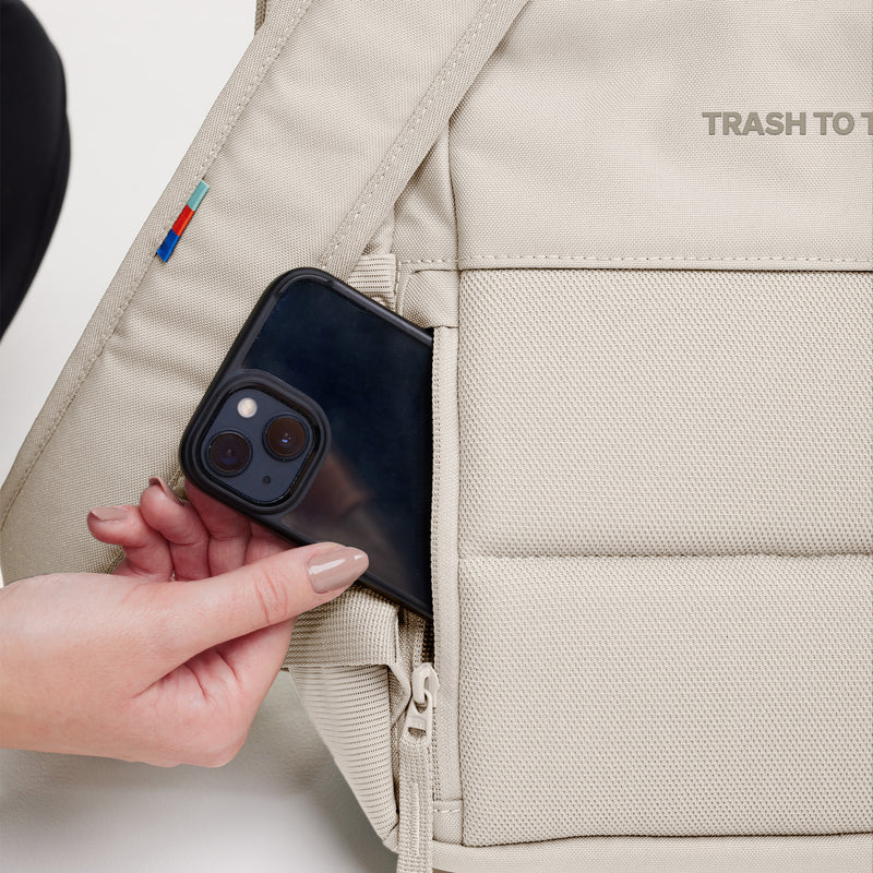DAYPACK 2.0 Rucksack in soft shell (warmes Cremeweiß) als Detailaufnahme beim Einstecken eines Smartphones.
