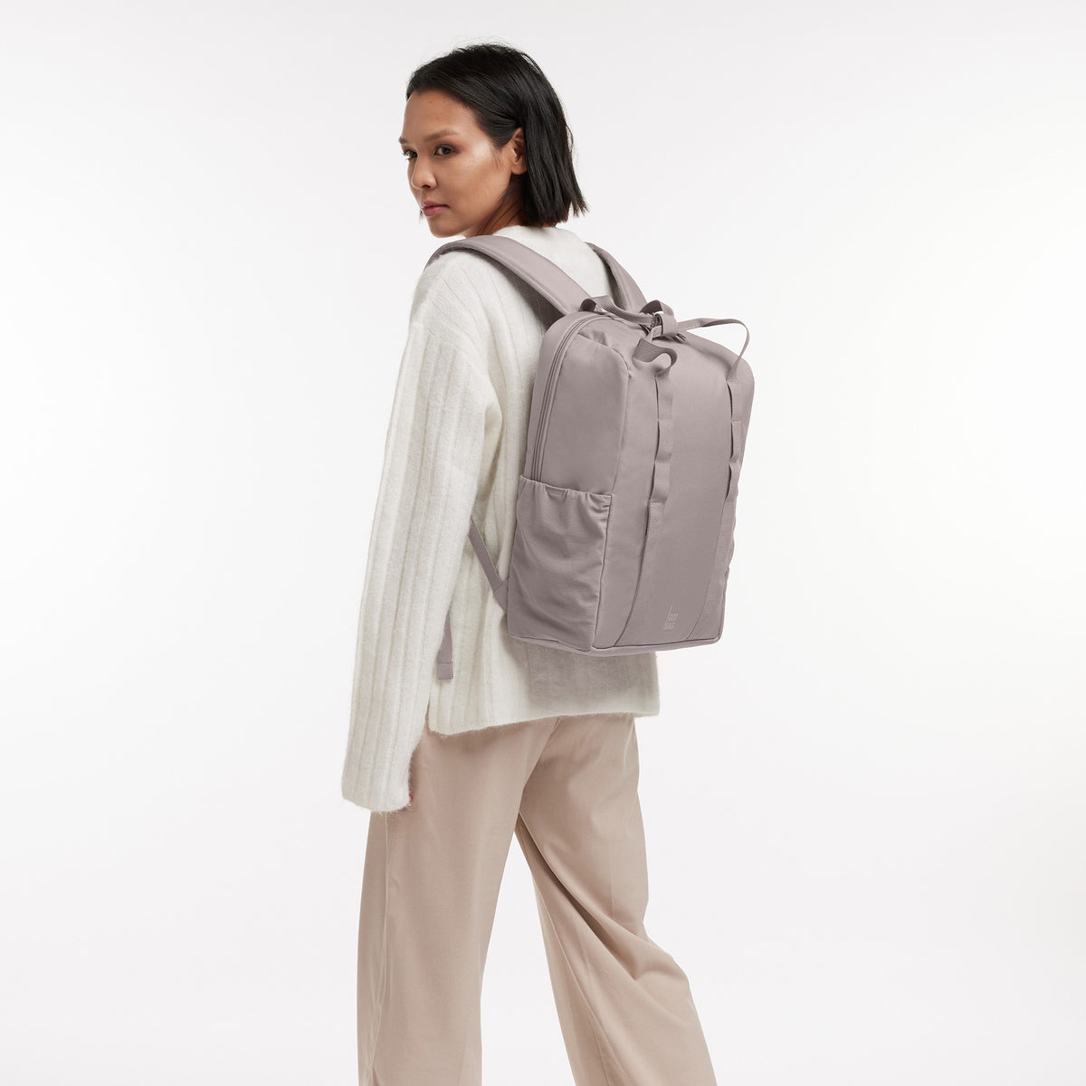DAYPACK LOOP Rucksack in seahorse (graues Pastellrosa) von einer Frau auf dem Rücken getragen.