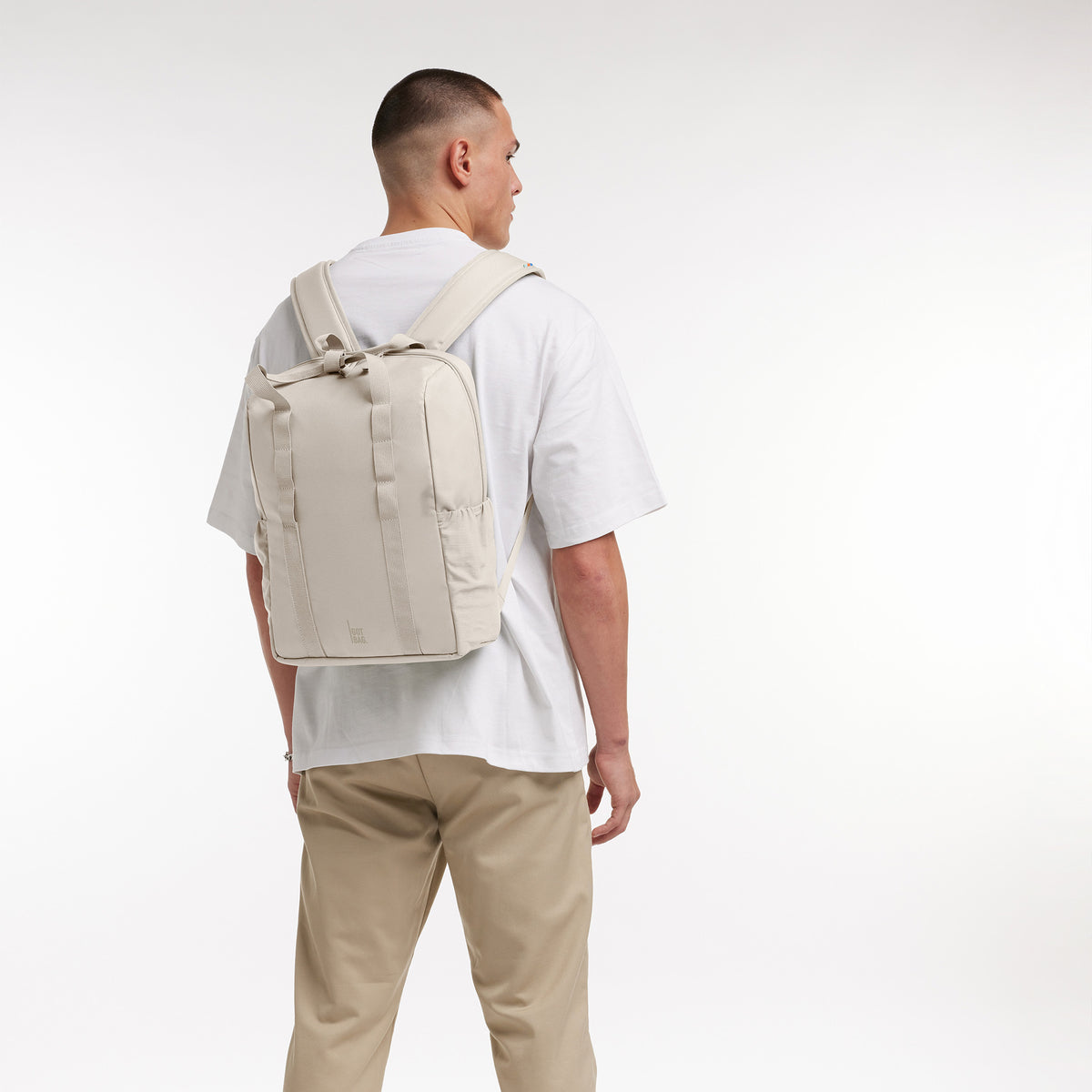 DAYPACK LOOP Rucksack in soft shell (warmes Cremeweiß) von einem Mann auf dem Rücken getragen.