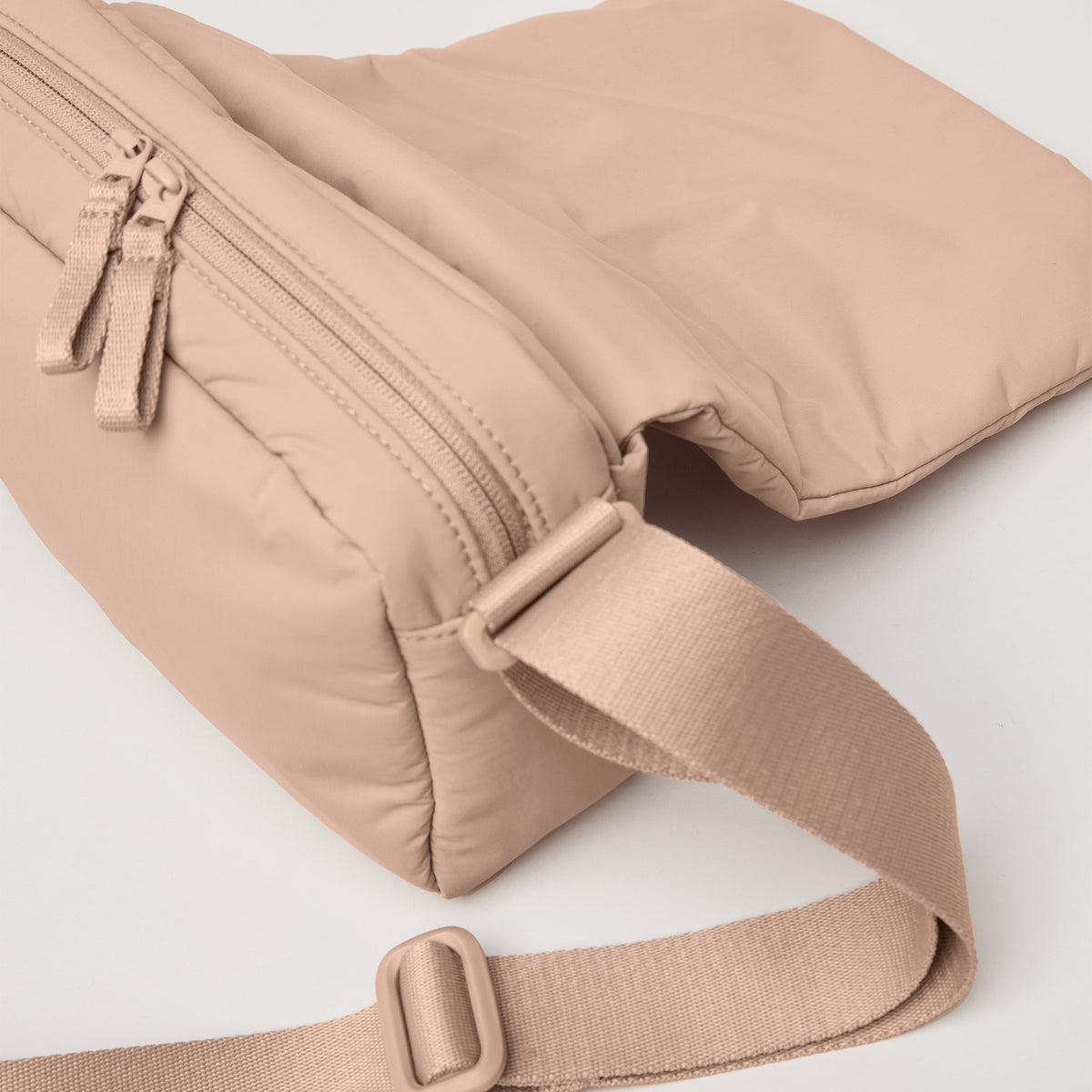 CLOUD CROSSBODY BAG Tasche in sandbar (warmes Beige mit rötlichem Unterton) als Detailaufnahme.