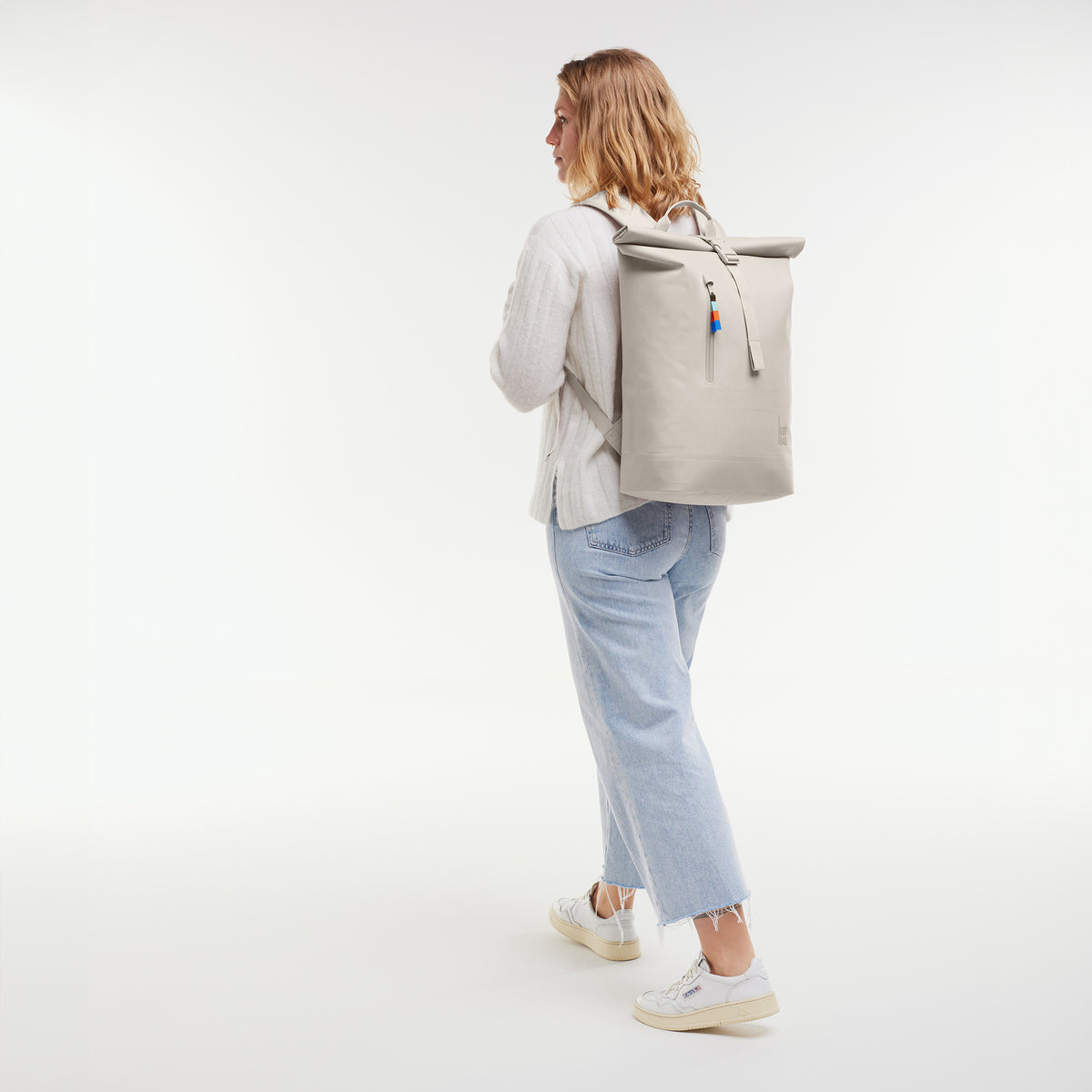 ROLLTOP LITE Rucksack in soft shell (warmes Cremeweiß) von einer Frau auf dem Rücken getragen.