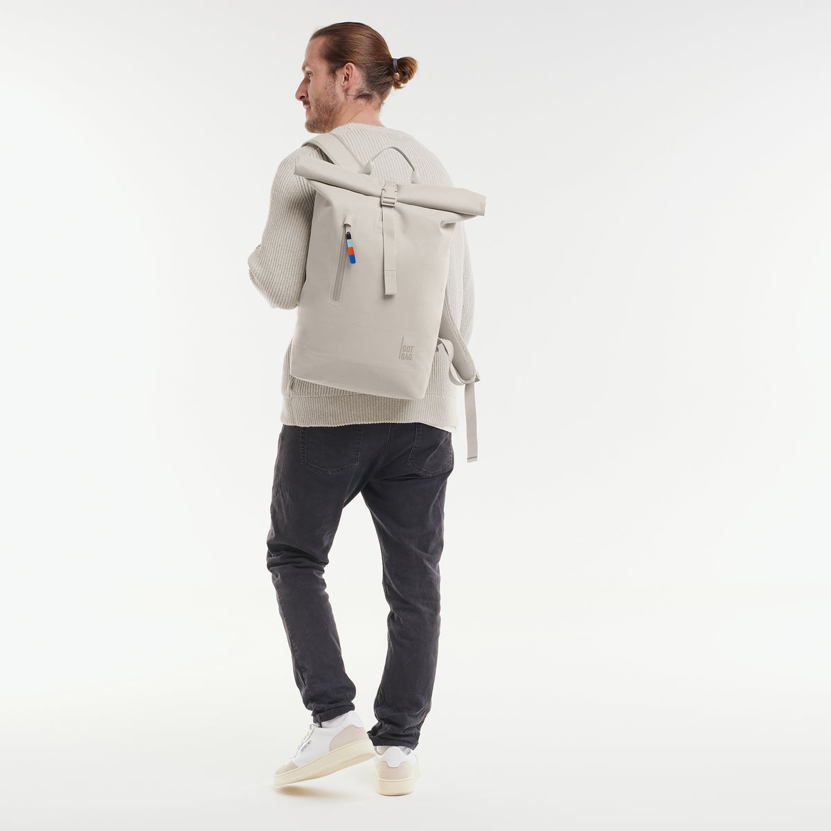 ROLLTOP LITE Rucksack in soft shell (warmes Cremeweiß) von einem Mann als Rucksack auf dem Rücken getragen.