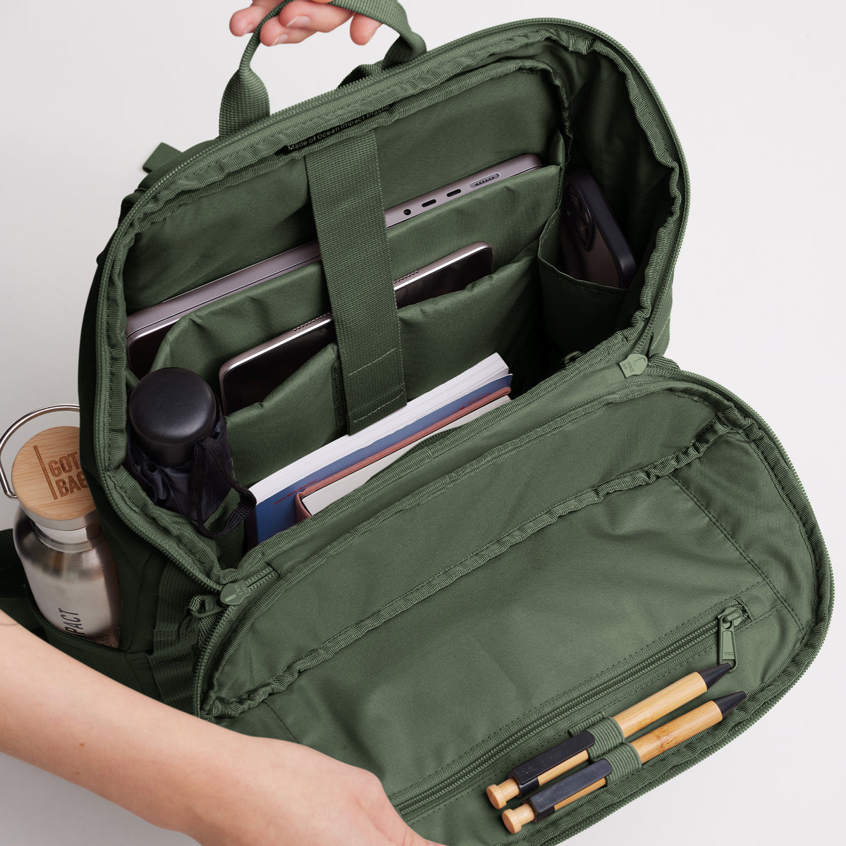PRO PACK Rucksack in algae (Dunkelgrün mit Graustich), geöffnet, Hände zeigen organisiertes Innenleben.
