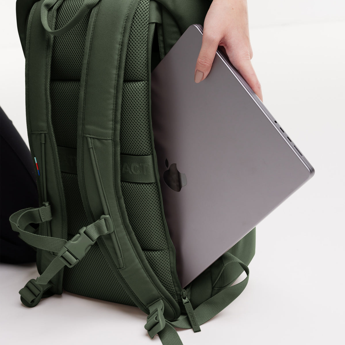 PRO PACK Rucksack in algae (Dunkelgrün mit Graustich), eine Frau steckt einen Laptop in das Fach.