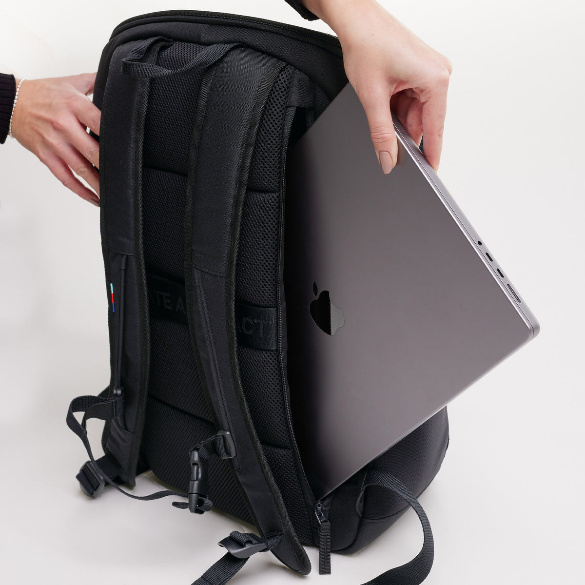 PRO PACK Rucksack in black (Schwarz): Eine Frau verstaut ein Notebook im Laptopfach.
